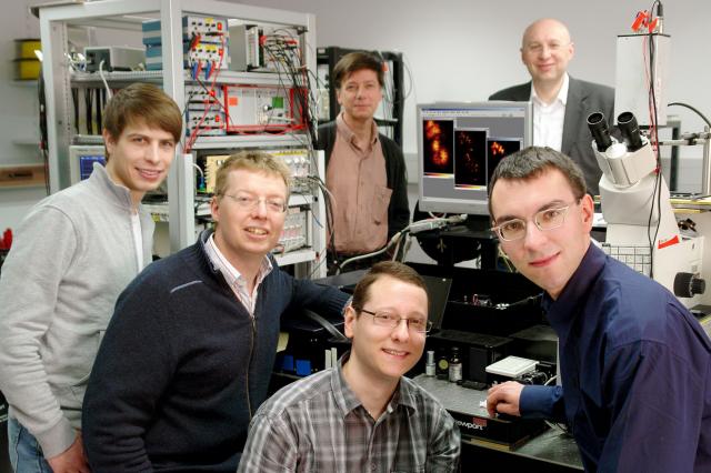 Die beteiligten Wissenschaftler vor dem STED-Mikroskop, mit dem das erste Video mit Auflösung jenseits der Beugungsgrenze (Nanoskala) aus lebenden Zellen aufgenommen wurde: Dirk Kamin, Volker Westphal, Silvio Rizzoli, Marcel Lauterbach (v. links nach rechts). Im Hintergrund: Reinhard Jahn (links) und Stefan W. Hell. (Foto: Böttcher, MPIbpc)