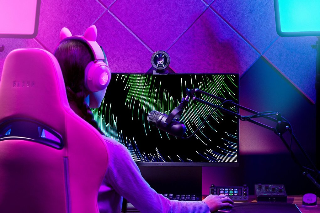Eine Frau sitzt vor einem Monitor, auf dem die Webcam Razer Kiyo Pro Ultra angebracht ist.