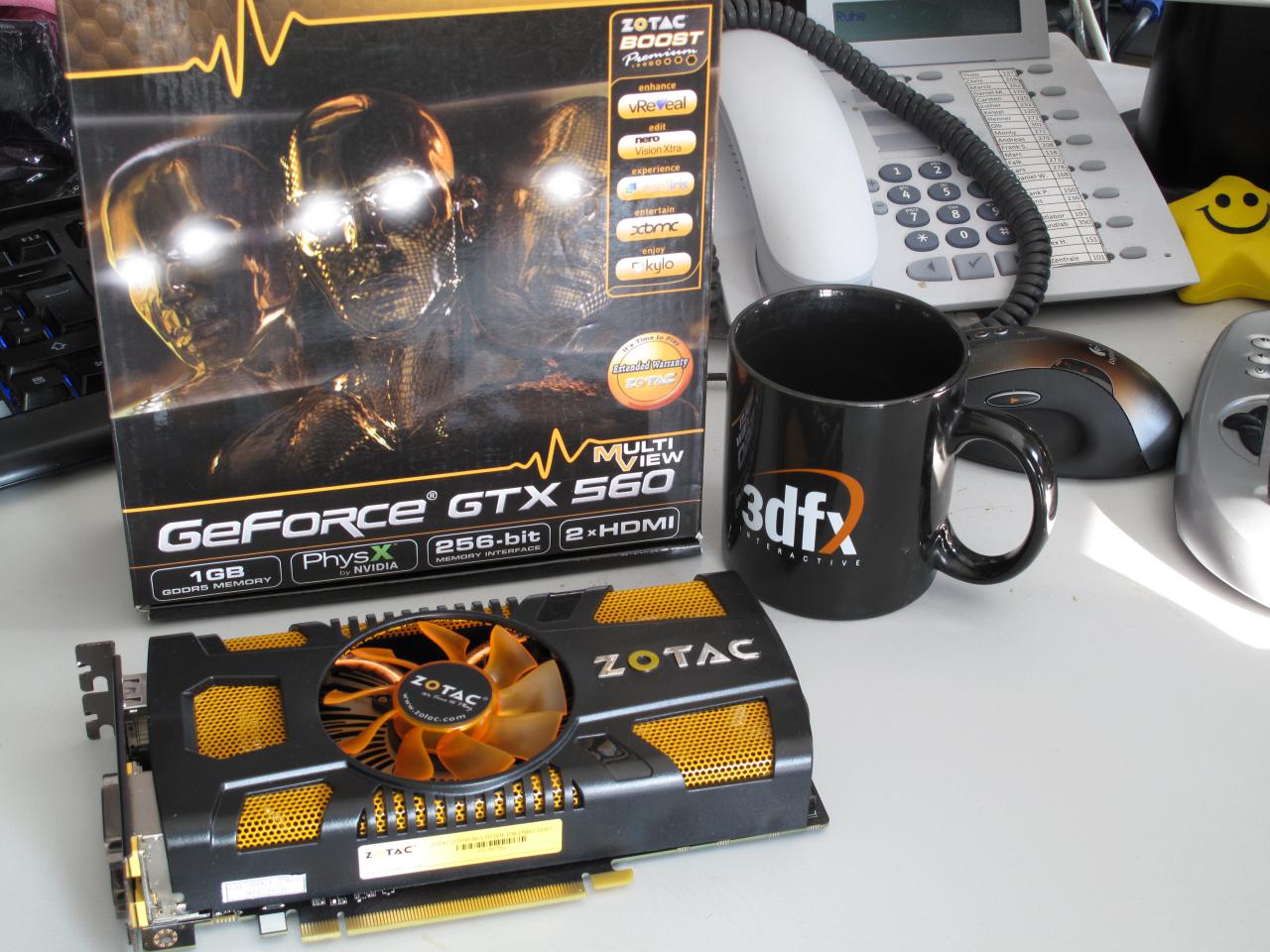 [21/10/2011] Auf Raffs Arbeitsplatz befindet sich schon wieder neue Arbeit in Form von Grafikkarten, die getestet werden wollen Hier im Bild: Zotac Geforce GTX 560 Multiview. Wie einst die Geforce GTX 460 3DP und die neuere GTX 550 Ti Multiview kann die GTX 560 Multiview ebenfalls über ein geteiltes Displayport-Signal bis zu drei Displays nativ ansteuern. Eine GPU-Übertaktung um 10 Megahertz rundet das Paket ab.