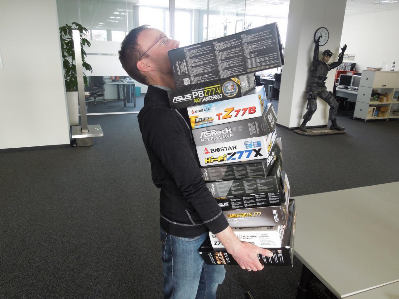 [28/03/2013] Noch eine Sockel-1155-Platine mehr und Daniel wäre woh nach hinten herüber gekippt. Na, etwas Gutes hat der fast schon überdimensionierte und der Größe des Herrn Möllendorf nur noch knapp entsprechende Mainboard-Stapel ja doch: Man sieht nicht, ob Daniel nun eher grimmig dreinschaut oder sich freut, dass er endlich anfangen darf die Hardware zu testen.