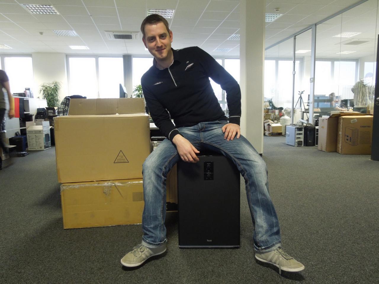 [06/12/2013] 8.12.2013: Phils Boxenparade zweiter Teil: Der Mega Subwoofer. Wenn Herr Reuther 5.1-Soundsysteme testet, kann das auch zum Vorteil der Kollegen sein. Steinhart beispielsweise war gerade auf der Suche nach seinem Bürostuhl, als er feststellte, dass es sich auf dem mächtigem Tiefbassspieler auch sehr bequem sitzen lässt. Und da Herr Staudacher Elektro-Sound mag hat er gerne ein kräftiges Bassbrummen unterm Gesäß.