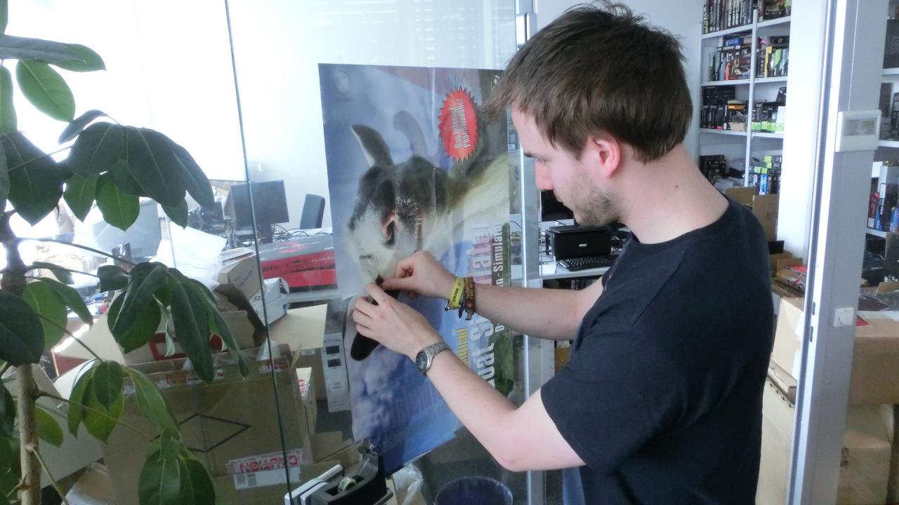 [24/04/2015] 26.4.2015: Sobald die Abgabe durch ist, kann sich unser Downsampling-Experte in leitender Funktion auch wieder um die Verschönerung der Redaktionsräume kümmern. Dass Raff neben Schlumpf Loske der größte Goat-Simulator-Fan der PCGH ist sollten Sie ja noch wissen. Mit Schrecken hat Herr Vötter festgestellt, dass der Lack bei unserem Poster an der Testlabor-Tür ab ist, sprich, die Vöttersche Devotionalie Risse bekommen hat (die Tasse nicht!). Und da Raff nicht nur auf Redaktionsambiente Wert legt, sondern auch Ordnung mag, hat er den Schaden so schnell behoben, wie er nur konnte.