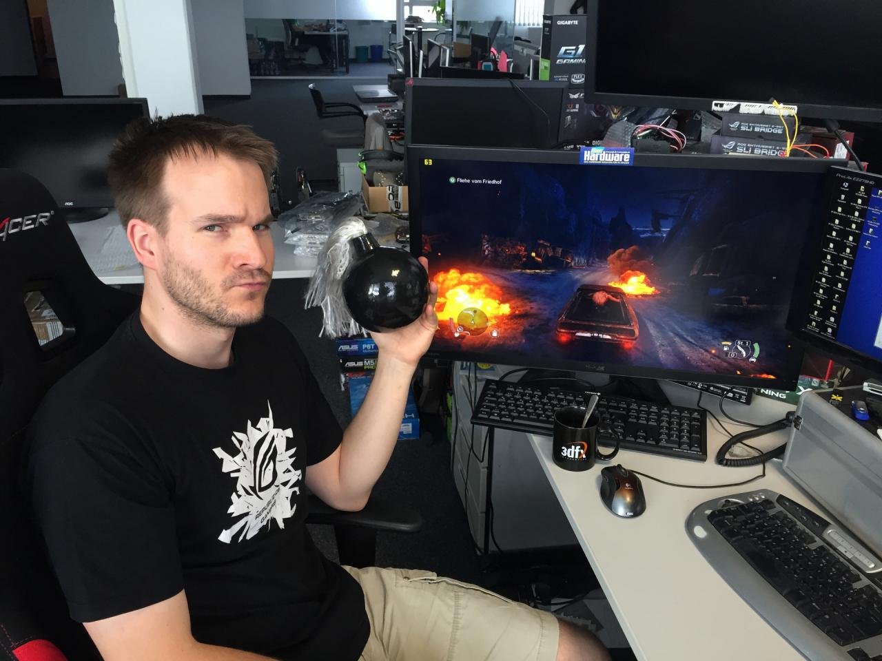 [04/09/2015] Auch wenn es auf diesem Bild so aussieht, als würde unser Grafik-Guru angefressen sein, weil er Mad Max mit 22 Grafikkarten benchen durfte/musste, trügt der Schein. Wie immer wollte Herr Vötter nämlich sein ganz spezielles Tässchen in die Kamera halten, das erschien unserem Reporter aber zu langweilig. Um den Unterhaltungswert dieses Bildes zu erhöhen, hat er ihm passend zu den Explosionen in der Benchmark-Szene eine Bombenattrappe in die Hand gedrückt und ihn aufgefordert einfach böse zu schauen - was ihm eindrucksvoll gelungen ist.