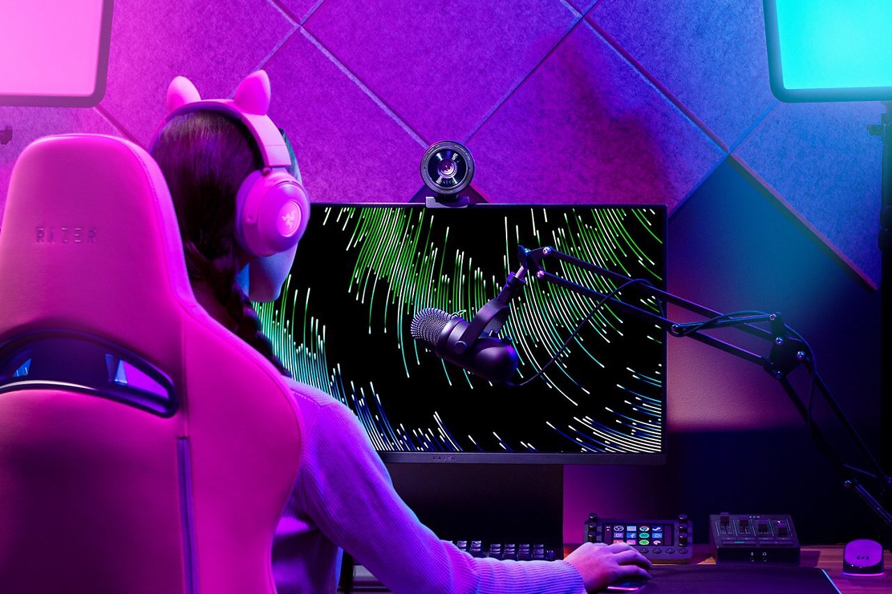 Eine Frau sitzt vor einem Monitor, auf dem die Webcam Razer Kiyo Pro Ultra angebracht ist.