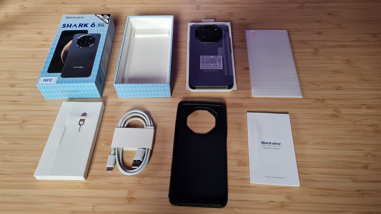 Ein schwarzes Handy samt Zubehör auf einem Holztisch.