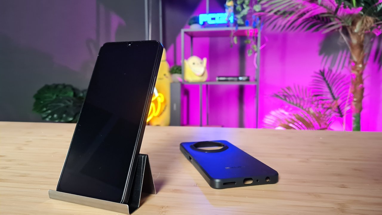 Ein schwarzes Handy samt Zubehör auf einem Holztisch.