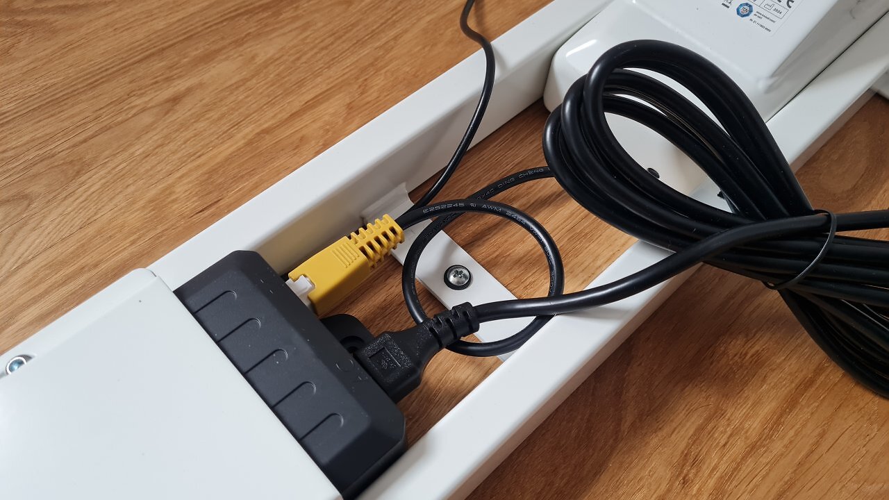 Die Unterseite eines höhenverstellbaren Schreibtischs mit Steuerbox und Kabeln.