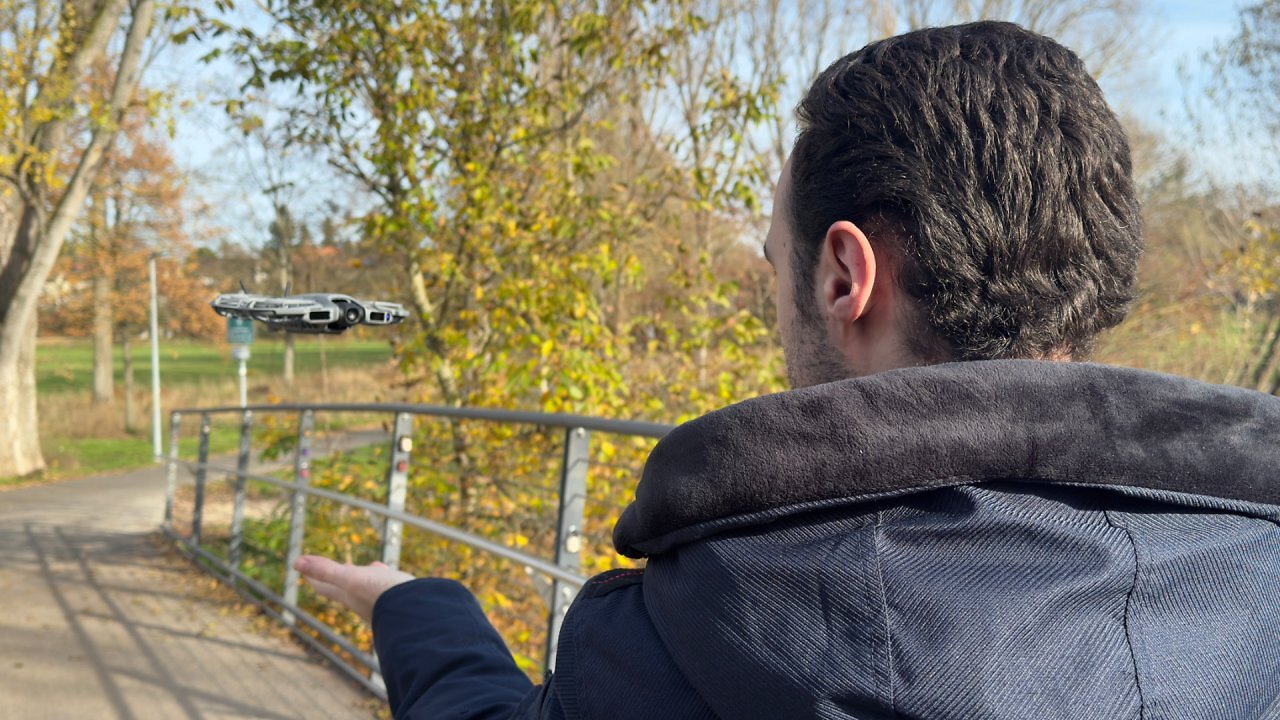 Eine Drohne schwebt vor einem Mann mit ausgestreckter Hand