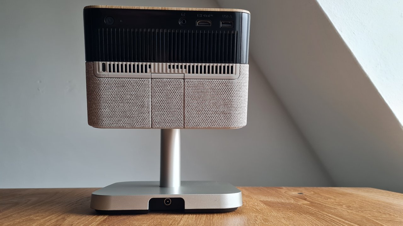Ein viereckiger Beamer mit Standfuß auf einem Holztisch