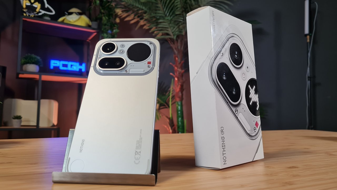 Ein Smartphone steht neben der Packung auf einem Holztisch