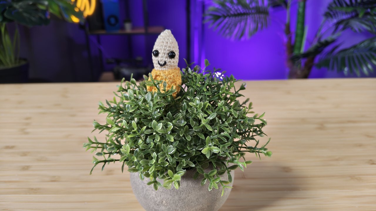 Eine gehäkelte Banane in einer Kunstpflanze