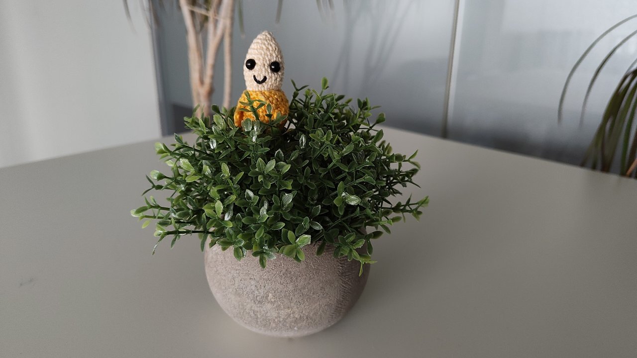 Eine gehäkelte Banane in einer Kunstpflanze