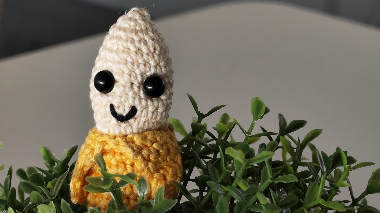Eine gehäkelte Banane in einer Kunstpflanze