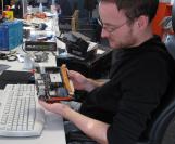 Daniel hält ein kleines Mainboard von Zotac in den Händen: Das A75-ITX Wifi im Mini-ITX-Format eignet sich für AMDs neuen Llano-Prozessor.