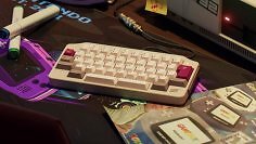 KeyBoy Advance kommt im Retro-GBA-Design in vielen Farben und mehreren Ausstattungen. Das Bild zeigt die Tastatur zwischen GBA-Accessoires und -Magazinen auf einem Schreibtisch.
