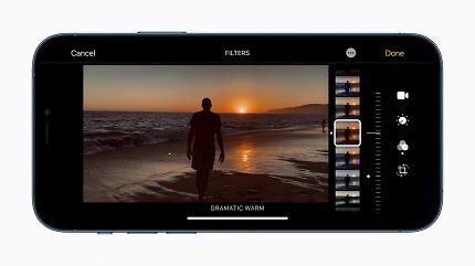 Ein seitlich gehaltenes Smartphone, das einen Sonnenuntergang am Strand fotografiert.