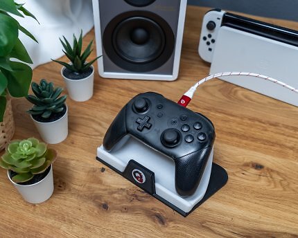 Tisch mit drei kleinen Sukkulente, Lautsprecher, Nintendo Switch und kabelgebundenem Controller.