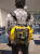 Der Prototyp wird wie ein Rucksack getragen. Die nackten Platinen lassen deutlich erkennen, dass das Gerät in einem frühen Entwicklungsstadium ist. In der linken Hand hält die Person etwas, das der Akku des Gerätes sein könnte. Über die Brille lässt sich nicht viel sagen.