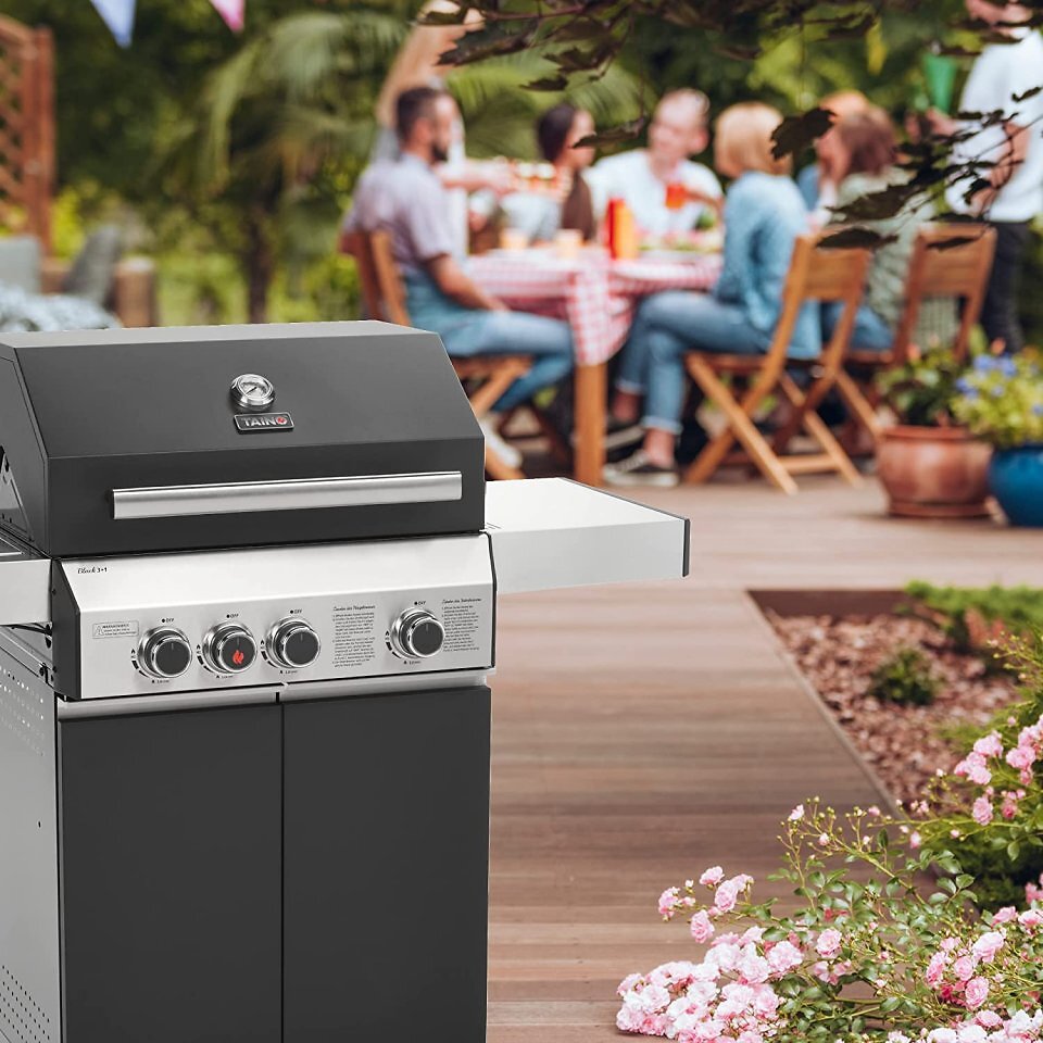 Ein grauer Gasgrill mit fröhlichen Leuten im Hintergrund